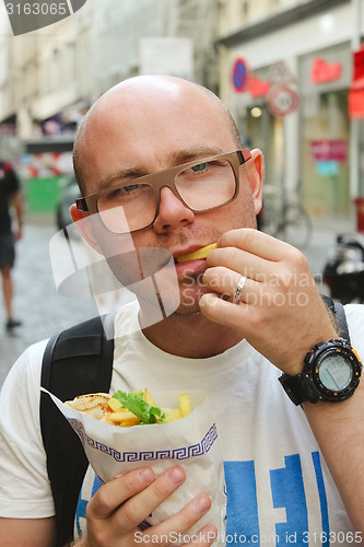 Image of portrait of bald man eating at street