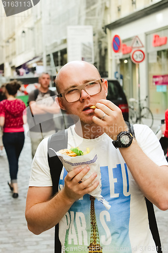 Image of portrait of bald man eating at street