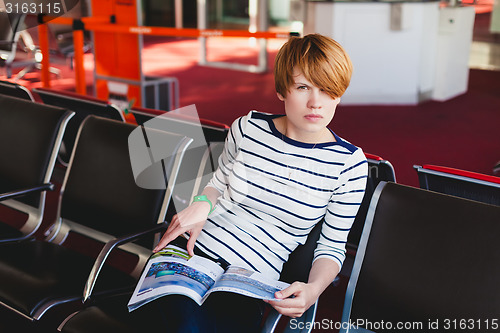 Image of woman reading newspaper at Charles de Gaulle airport,