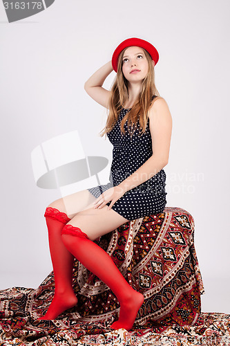 Image of young girl holds a red hat on her head