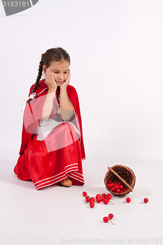 Image of The little girl spilled cherries is sad