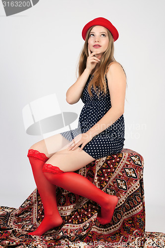 Image of young girl holds a red hat on her head