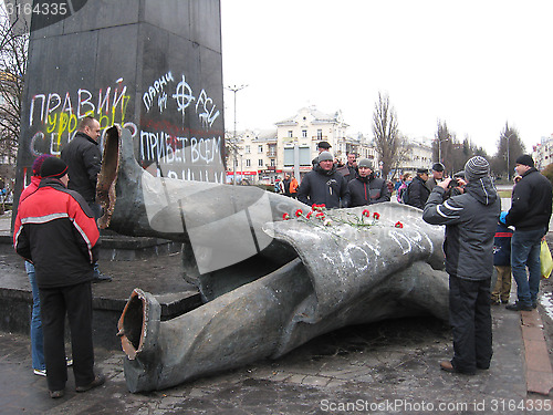 Image of people near thrown big bronze monument to Lenin