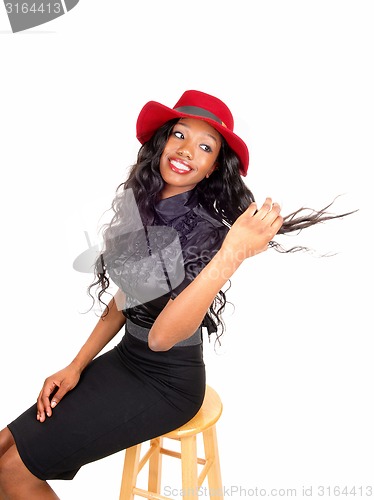 Image of Black woman with red hat sitting on chair.