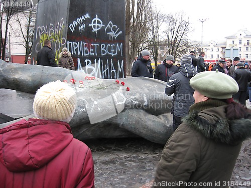 Image of people near thrown bronze monument to Lenin