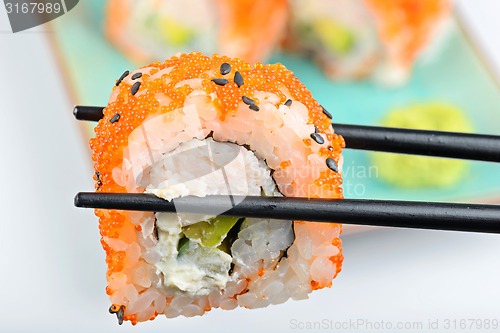 Image of Sushi roll with black chopsticks 