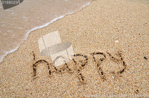Image of Happy word written on sandy the beach