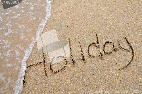 Image of Holiday word written on sandy beach