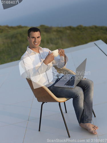 Image of relaxed young man at home on balcony