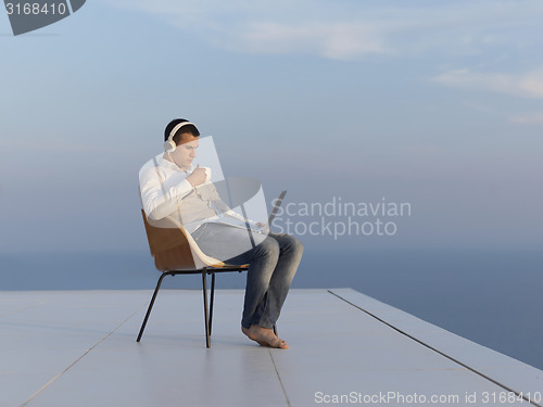 Image of relaxed young man at home on balcony