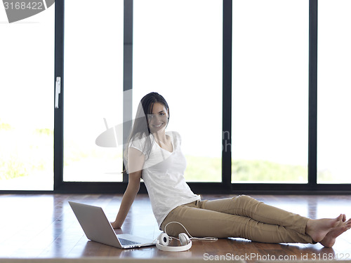 Image of relaxed young woman at home working on laptop computer