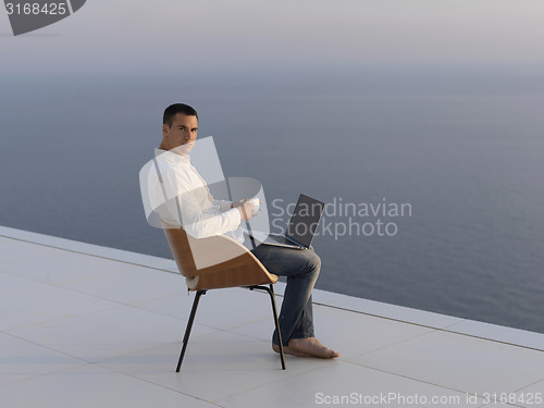 Image of relaxed young man at home on balcony