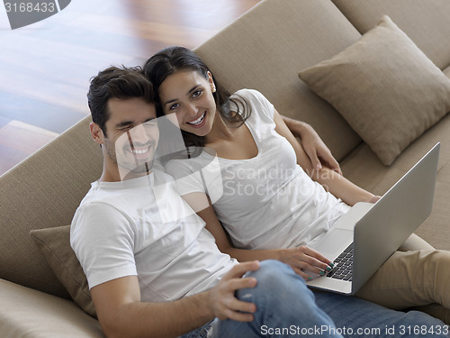 Image of relaxed young couple working on laptop computer at home