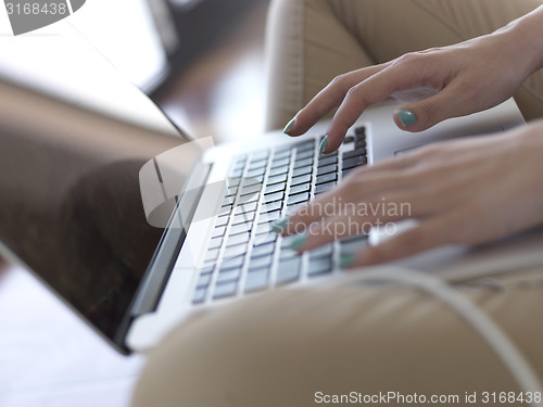 Image of relaxed young woman at home working on laptop computer