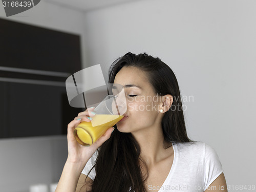 Image of woman drinking juice in her kitchen