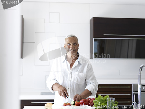 Image of man cooking at home preparing salad in kitchen