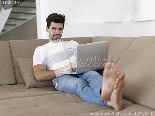 Image of Man Relaxing On Sofa With Laptop