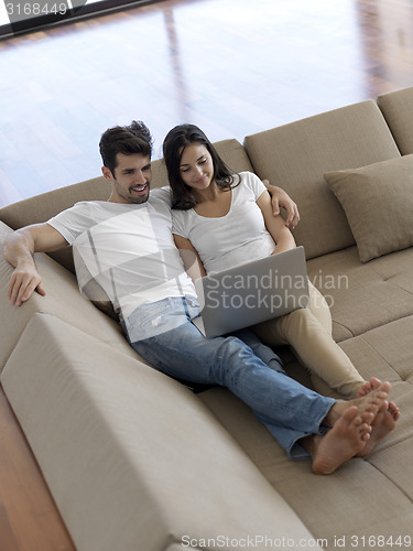 Image of relaxed young couple working on laptop computer at home