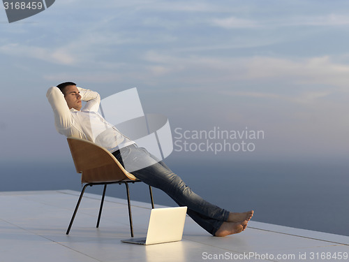 Image of relaxed young man at home on balcony