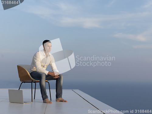 Image of relaxed young man at home on balcony