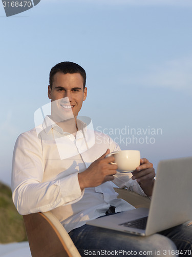 Image of relaxed young man at home on balcony
