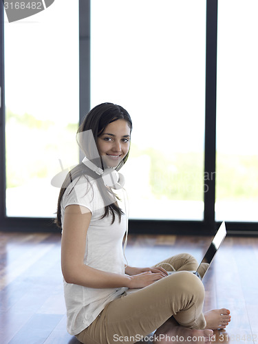 Image of relaxed young woman at home working on laptop computer