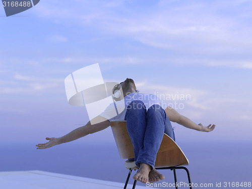 Image of relaxed young man at home on balcony