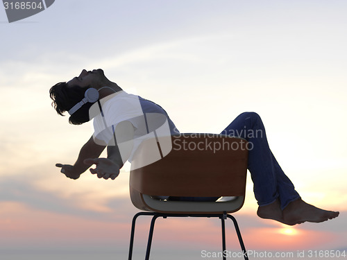 Image of relaxed young man at home on balcony