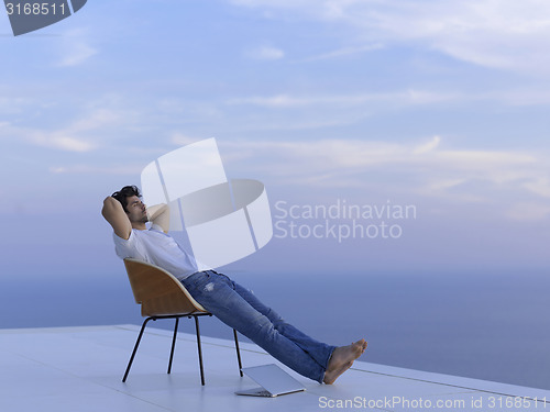 Image of relaxed young man at home on balcony