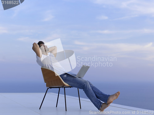 Image of relaxed young man at home on balcony
