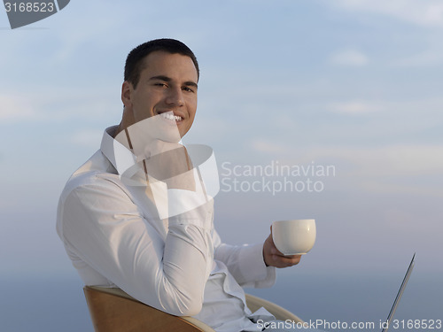 Image of relaxed young man at home on balcony