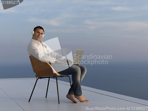 Image of relaxed young man at home on balcony