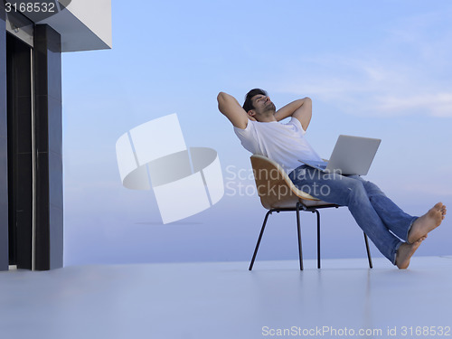 Image of relaxed young man at home on balcony