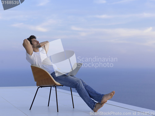 Image of relaxed young man at home on balcony