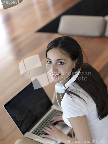 Image of relaxed young woman at home working on laptop computer