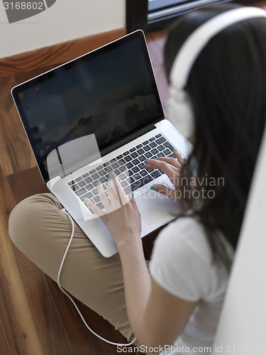 Image of relaxed young woman at home working on laptop computer