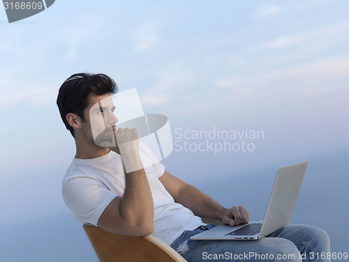 Image of relaxed young man at home on balcony