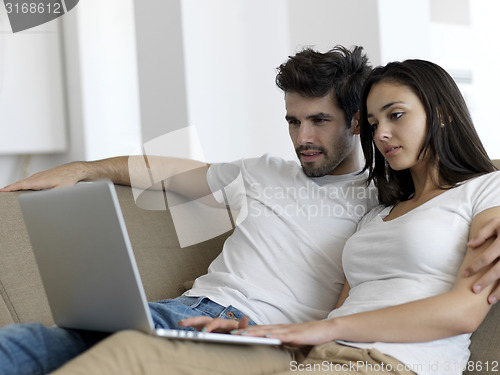 Image of relaxed young couple working on laptop computer at home