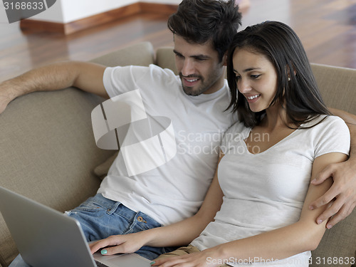 Image of relaxed young couple working on laptop computer at home