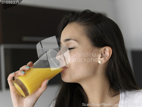 Image of woman drinking juice in her kitchen