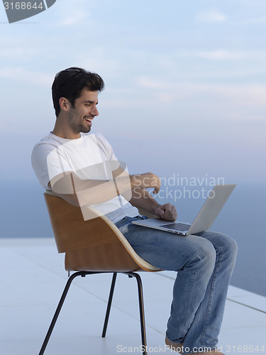 Image of relaxed young man at home on balcony