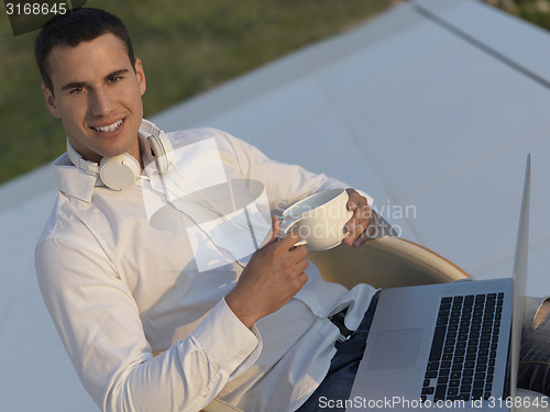 Image of relaxed young man at home on balcony