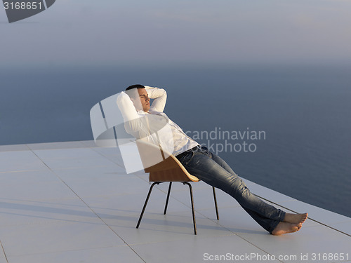 Image of relaxed young man at home on balcony