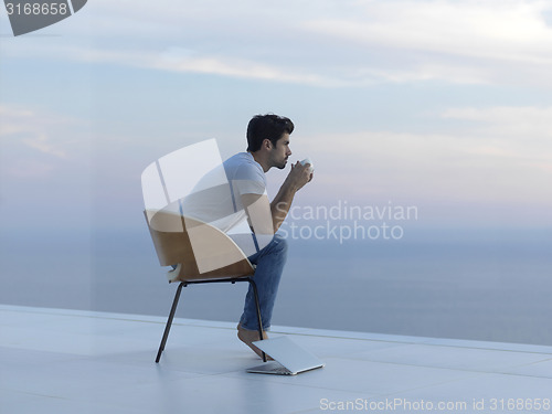 Image of relaxed young man at home on balcony