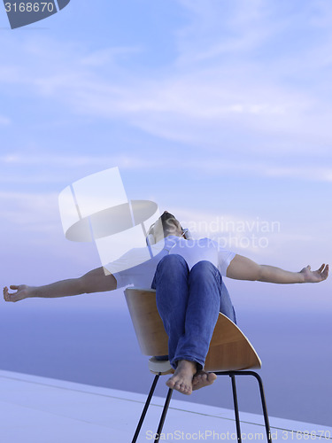 Image of relaxed young man at home on balcony