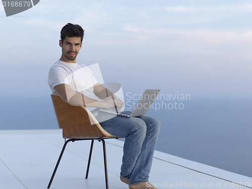 Image of relaxed young man at home on balcony