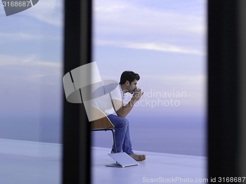 Image of relaxed young man at home on balcony