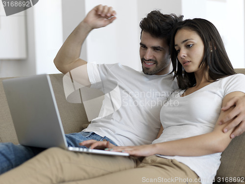 Image of relaxed young couple working on laptop computer at home