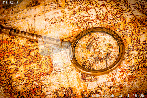 Image of Vintage magnifying glass lies on an ancient world map