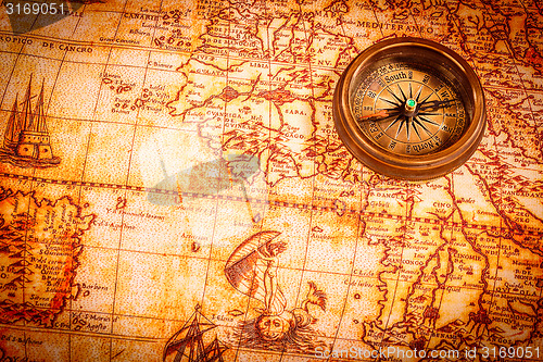 Image of Vintage compass lies on an ancient world map.